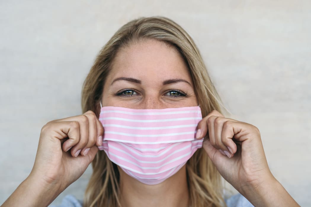Young woman wearing pink face mask portrait - Blonde female using protective facemask for preventing spread of corona virus