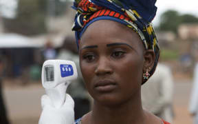 A health worker checks a woman entering Mali from Guinea for signs of Ebola.