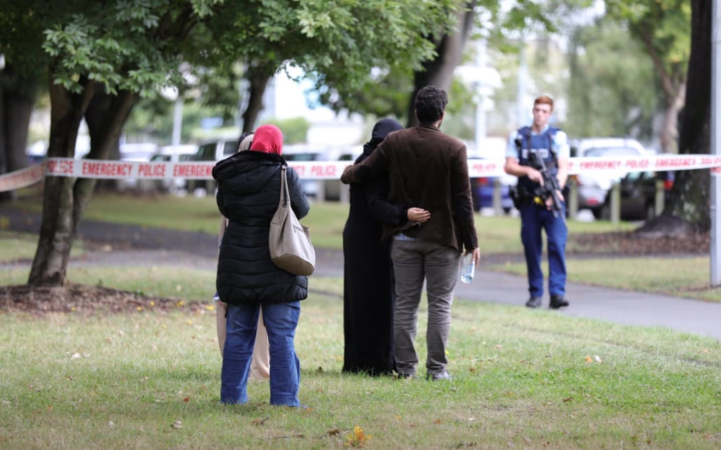 Police taping off the street, people reunited at the edge of the cordon