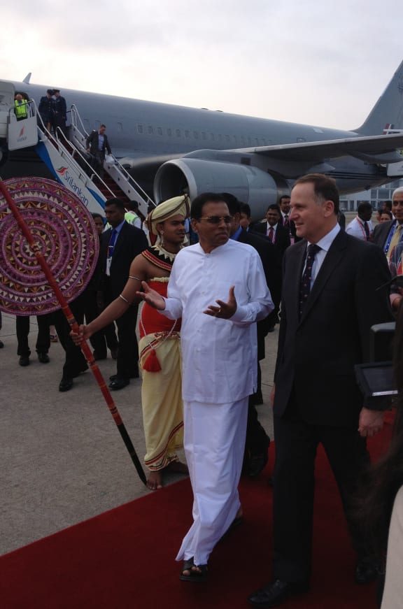 John Key, right, is welcomed at the airport in Colombo.