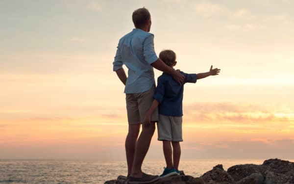 Father and son looking on sunset at the sea