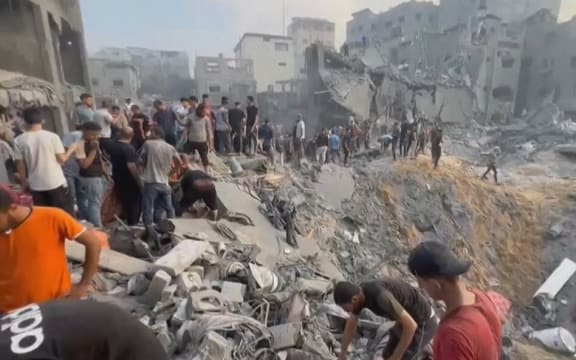 This image grab taken from AFPTV video footage shows Palestinians looking for survivors in a crater following a strike on a refugee camp in Jabalia on the northern Gaza Strip, on 31 October, 2023, amid relentless Israeli bombardment of the Palestinian territory.