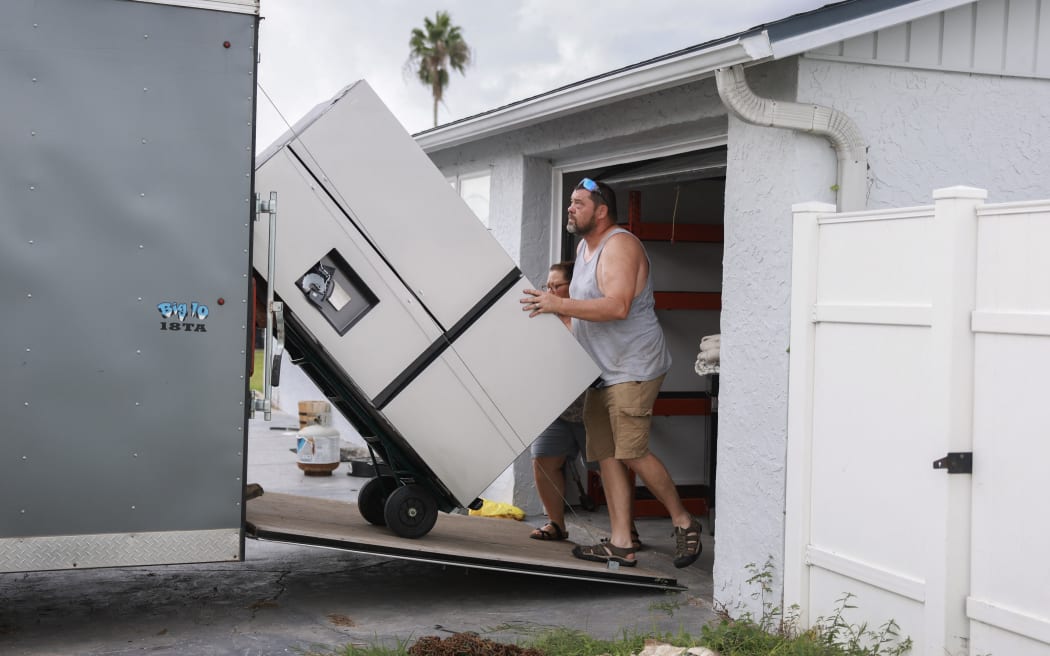 Holly Sexton and Paul Sexton move a fridge into a trailer as they remove most of their belongings from their home, ahead of the arrival of Hurricane Helene on 25 September, 2024 in Port Richey, Florida. Sexton said she would rather move everything out than have to replace items if the house floods.