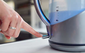Close Up Of Woman Pressing Power Switch On Electric Kettle To Save Energy At Home