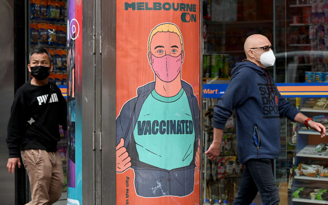 People walk past a poster encouraging vaccinations in Melbourne.