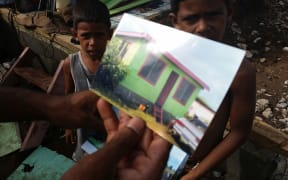 Mohammed Nadim shows photos of the house that was destroyed by Winston.