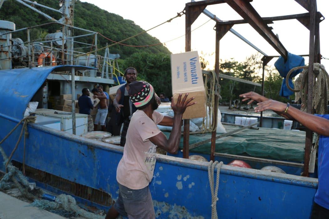 Vanuatu disaster officers and the crew of the ship One People form a chain gang to load supplies for evacuees on Ambae.