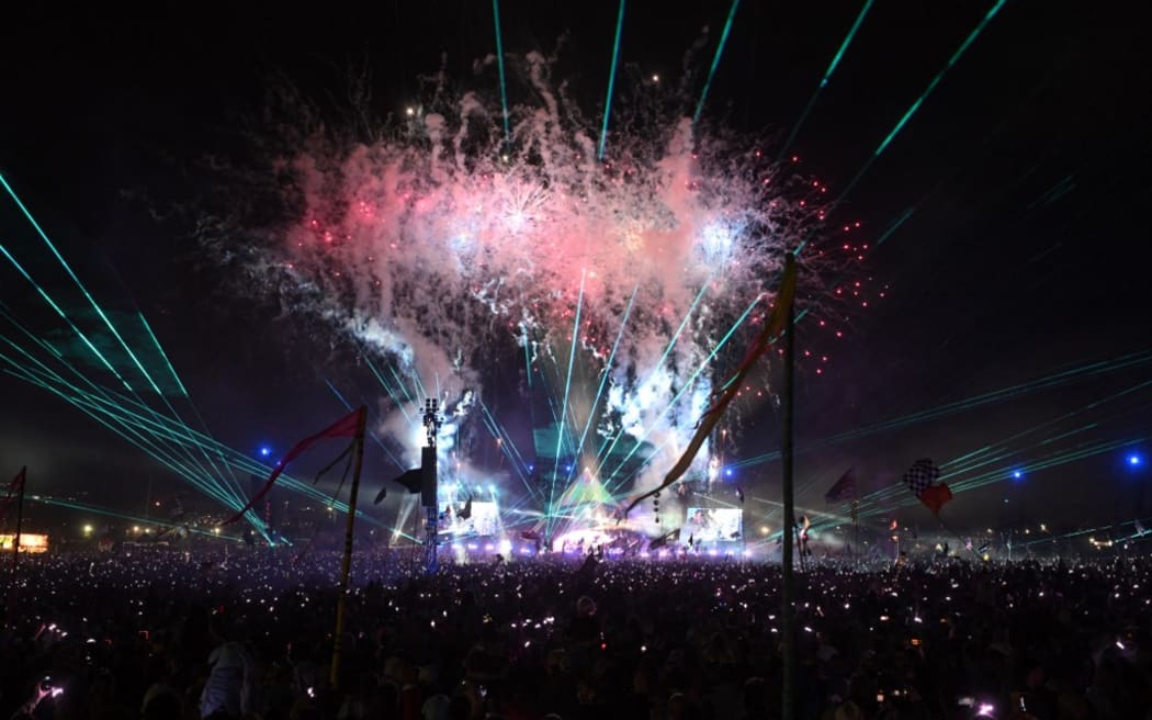 Fireworks illuminate the sky as crowds listen to Coldplay perform on the Pyramid Stage.