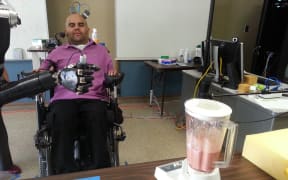 Erik Sorto uses a robotic arm controlled by his thoughts to operate a blender.