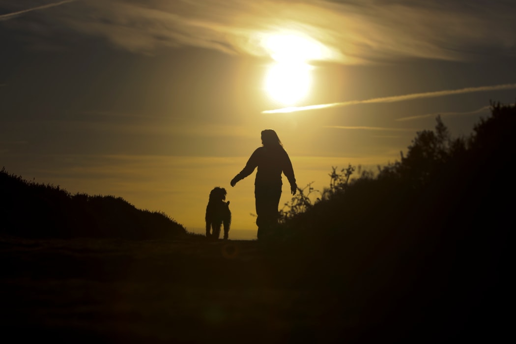 Woman walking her dog at Sunset