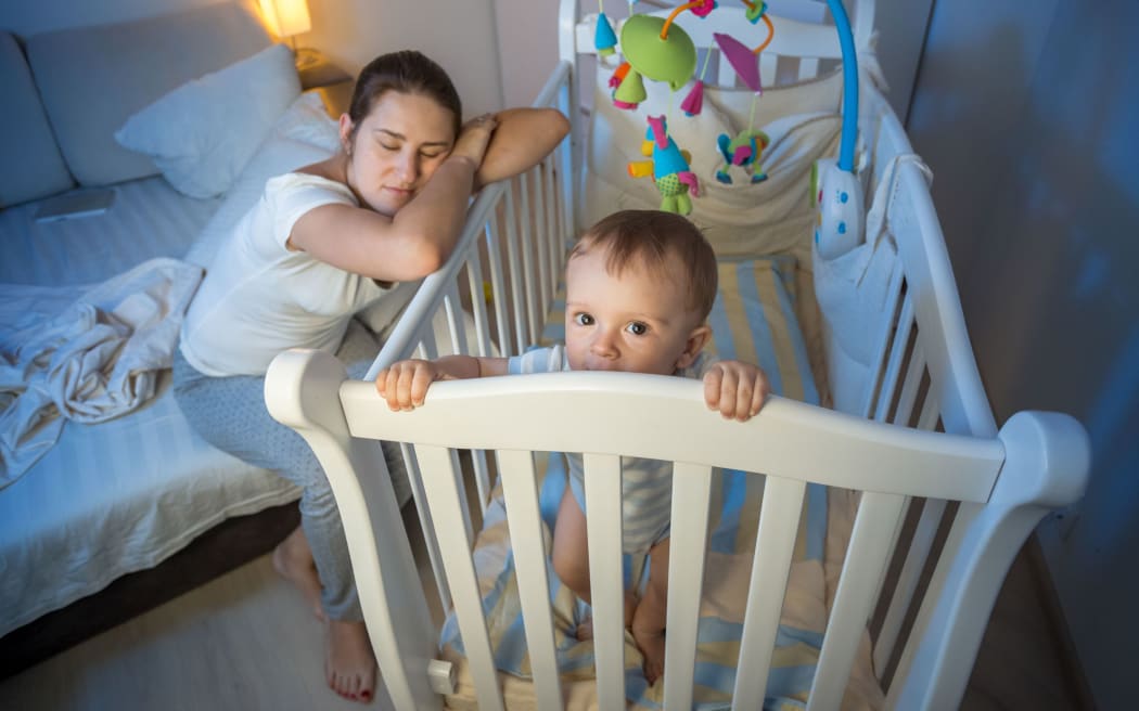 62246101 - young tired mother got asleep next to baby's crib