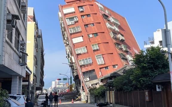 This photo taken by Taiwan's Central News Agency (CNA) on April 3, 2024 shows people looking at a damaged building in Hualien, after a major earthquake hit Taiwan's east. A major 7.4-magnitude earthquake hit Taiwan's east on the morning of April 3, prompting tsunami warnings for the self-ruled island as well as parts of southern Japan and the Philippines. (Photo by CNA / AFP) / China OUT - Macau OUT - Taiwan OUT / HONG KONG OUT - RESTRICTED TO EDITORIAL USE