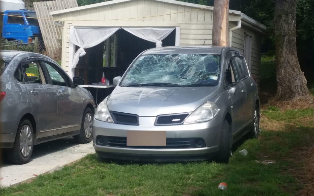 Police are examining the property, where smashed cars sit in the driveway and glass bottles are lying on the front lawn.