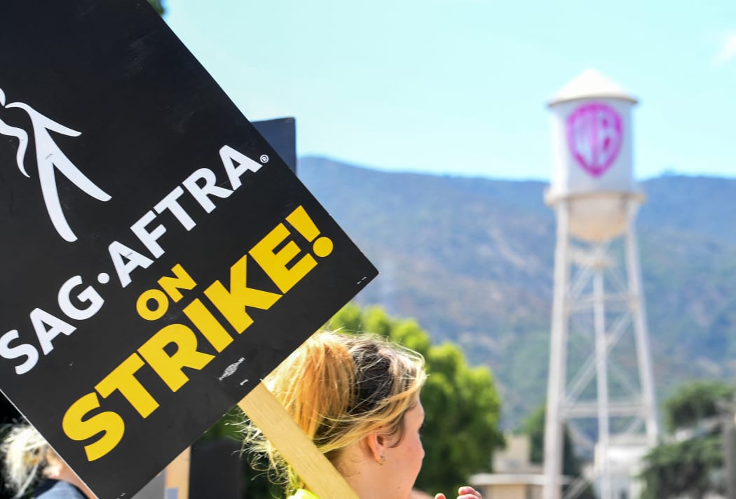 Members of the Writers Guild of America and the Screen Actors Guild walk a picket line outside of Warner Bros Studio in Burbank, California, on July 26, 2023. Tens of thousands of Hollywood actors went on strike at midnight July 14, 2023, effectively bringing the giant movie and television business to a halt as they join writers in the first industry-wide walkout for 63 years. (Photo by VALERIE MACON / AFP)
