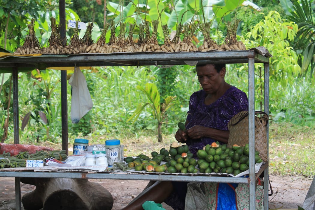 A woman in Papua New Guinea selling betel nut and accessories by the roadside.