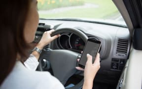 A portrait of a woman  using cellphone inside a car, taken from behind