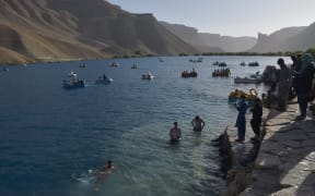 In this picture taken on July 14, 2022, Afghan tourists cool off and enjoy boat rides at Ban e-Amir Lake in Bamyan province. (Photo by Ahmad SAHEL ARMAN / AFP)
