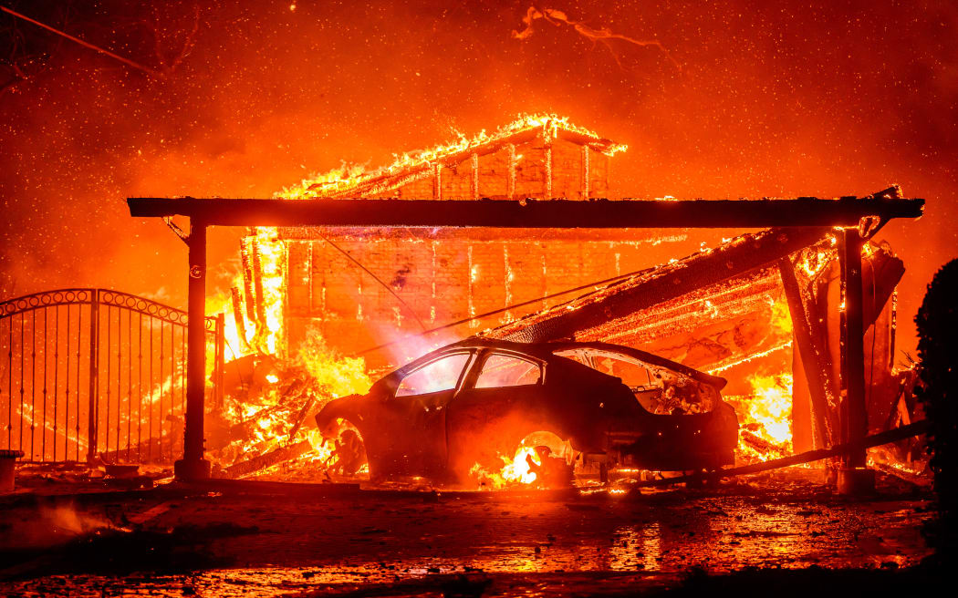 A car and home burn during the Eaton fire in the Altadena area of Los Angeles County, California on January 8, 2025. (Photo by JOSH EDELSON / AFP)