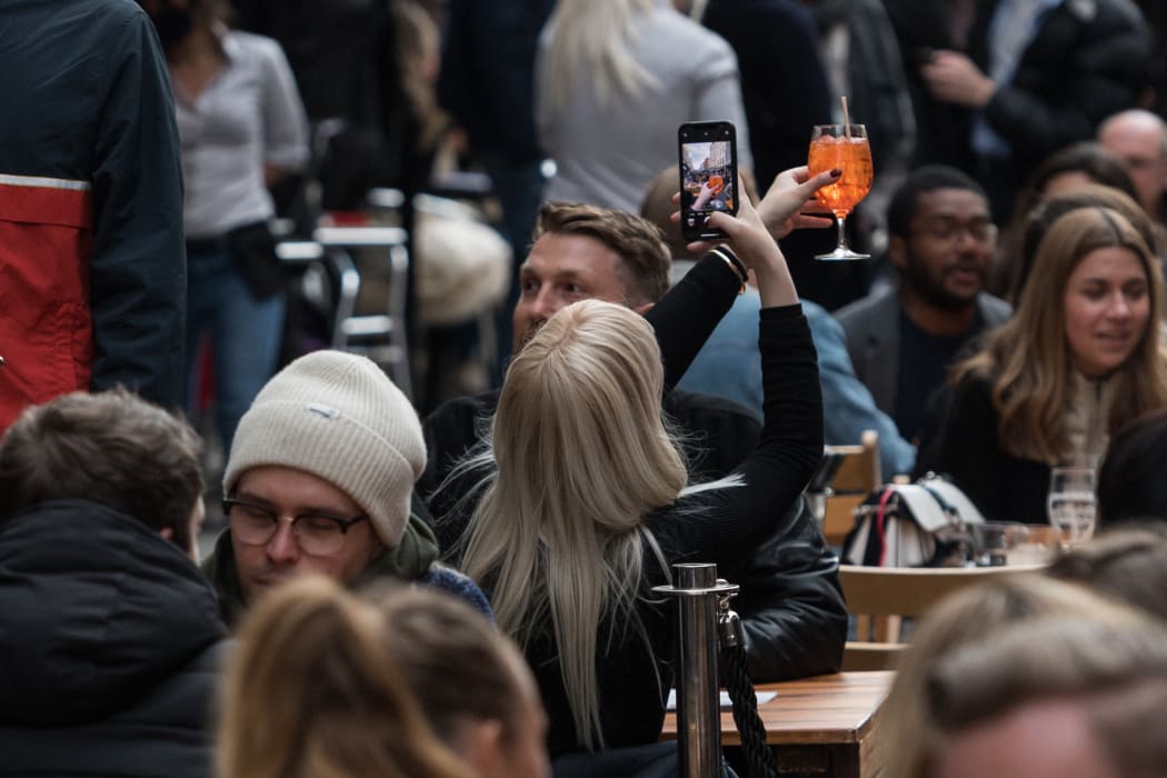 A woman takes a picture of her drink in Soho as outdoor hospitality venues open their premises to customers after being closed for over three months under coronavirus lockdown.