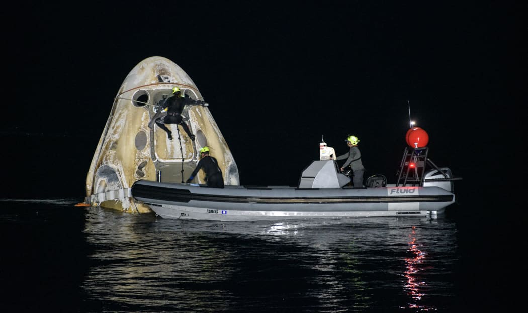 Support teams working around the SpaceX Crew Dragon Resilience spacecraft shortly after it landed