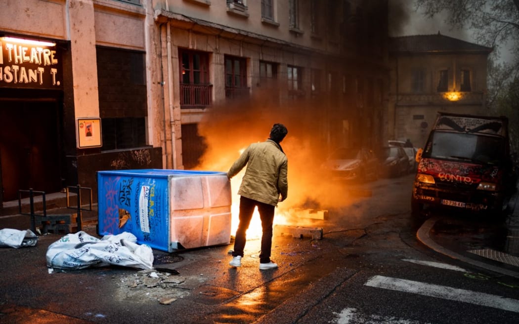 Lyon, France, 2023-04-14. A passerby stands in front of a burning barricade during the demonstration against the pension reform, after the validation of the reform by the constitutional council. Photography by Nicolas Liponne / Hans Lucas.
Lyon, France, 2023-04-14. Un passant se tient devant une barricade en feu lors de la manifestation contre la reforme des retraites, apres la validation de la reforme par le conseil constitutionnel. Photographie de Nicolas Liponne / Hans Lucas. (Photo by Nicolas Liponne / Hans Lucas / Hans Lucas via AFP)