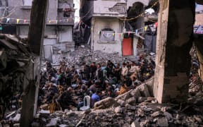 People gather for the iftar, or fast-breaking meal, on the first day of the Muslim holy fasting month of Ramadan in Jabalia in the northern Gaza Strip on March 1, 2025 by the rubble of collapsed buildings that were destroyed during the war between Israel and Hamas, amid the ongoing truce. (Photo by Bashar TALEB / AFP)