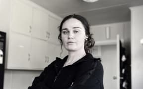 Erin Speedy of Mission Homefront stands crossing their arms in a house.