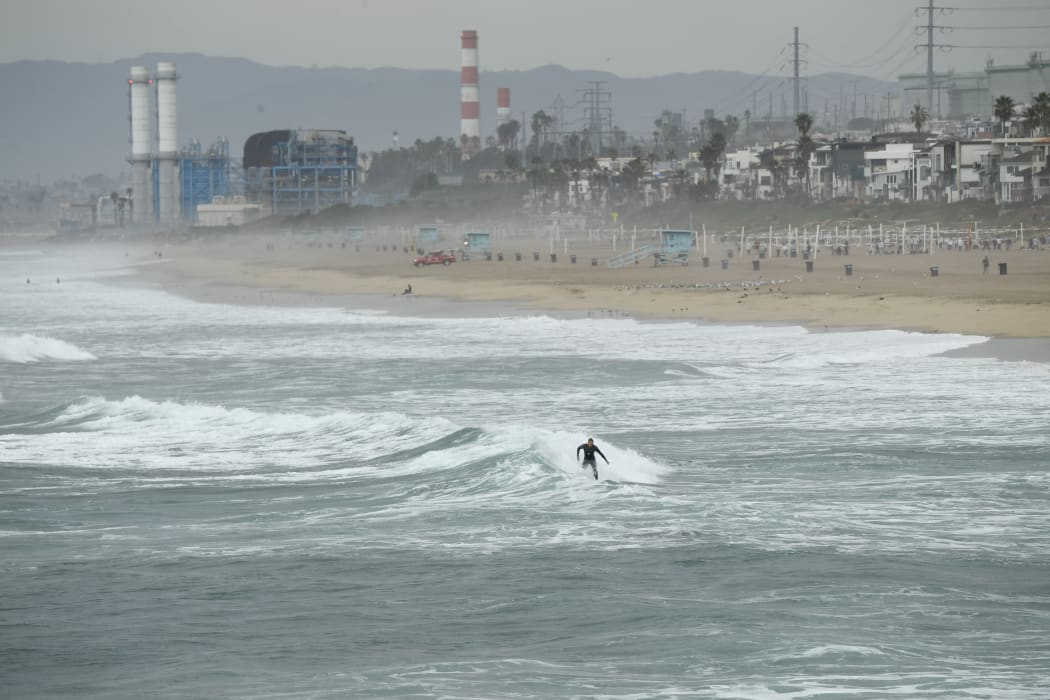 A surfer catches a wave in Manhattan Beach, California, on January 15, 2022. The US National Weather Service issued tsunami advisories for the entire west coast of the United States following a massive volcanic eruption across the Pacific Ocean in Tonga.