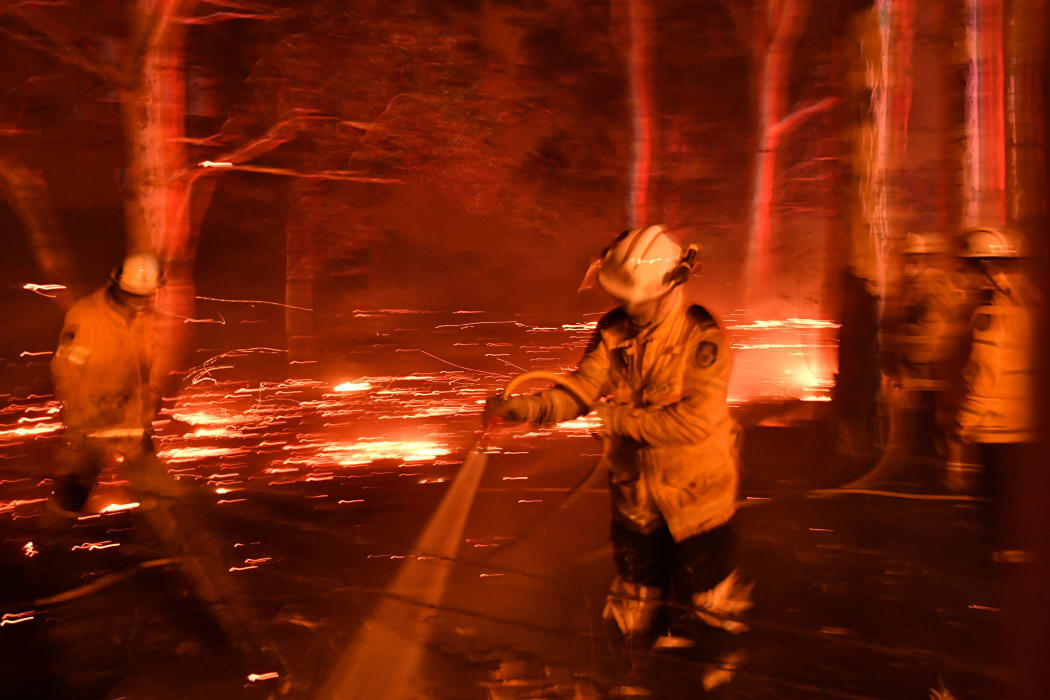 Firefighters hose down the area as they battle against bushfires around the town of Nowra in the Australian state of New South Wales on December 31, 2019.