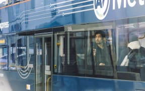 An Asian man on a bus on Wellesley Street in Auckland CBD, July 2024.