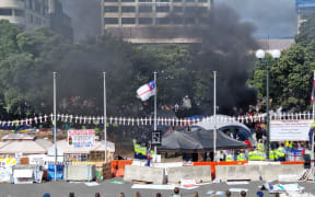 Something is set on fire but police come in with fire extinguishers to put it out.