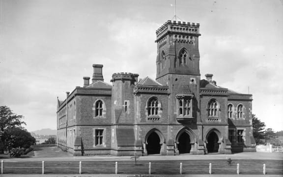 Front view of the Supreme Court from Waterloo Quadrant, with a glimpse of the harbour and Rangitoto in the background. Year: 1921.