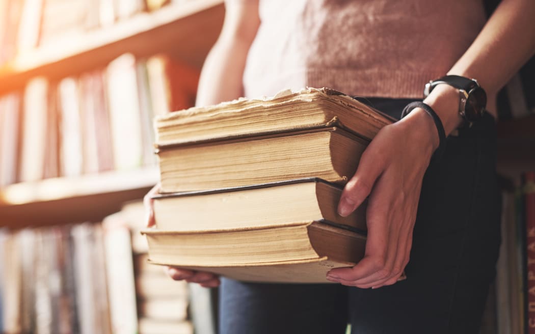 A young girl student looking for literature near the bookshelves in the old library,