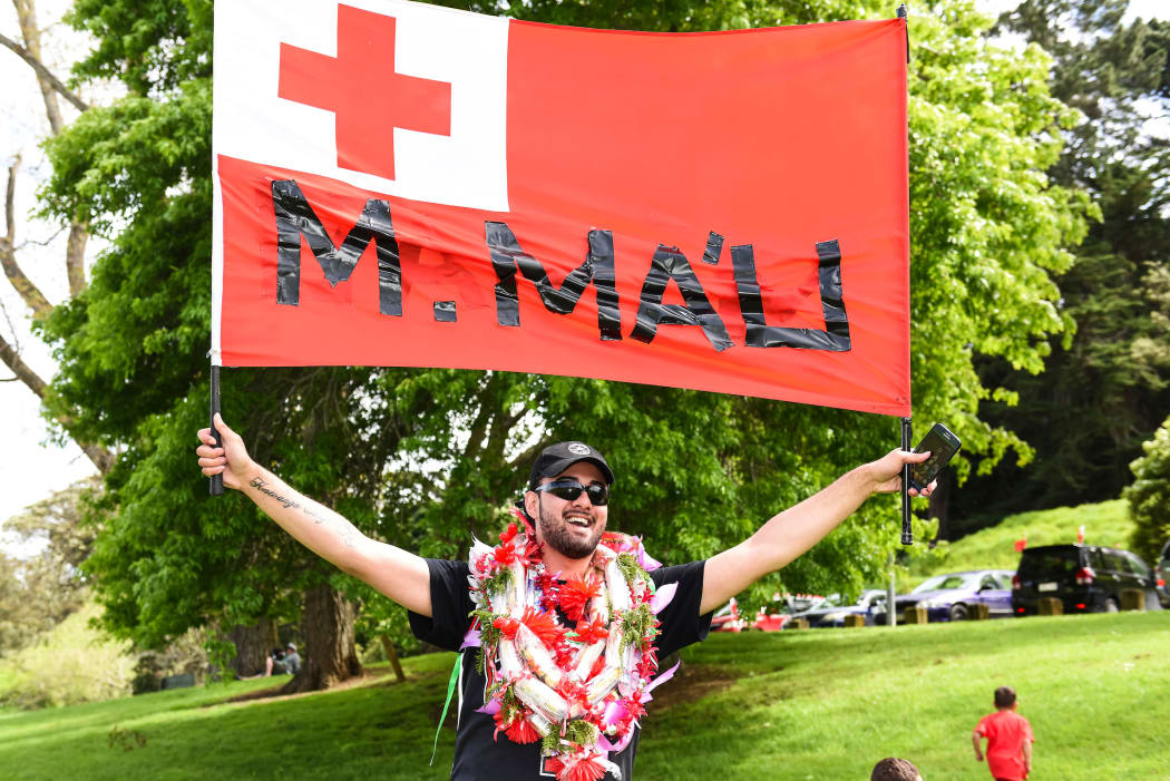 A fan holds a Tongan flag cheering on player Manu Ma'u.