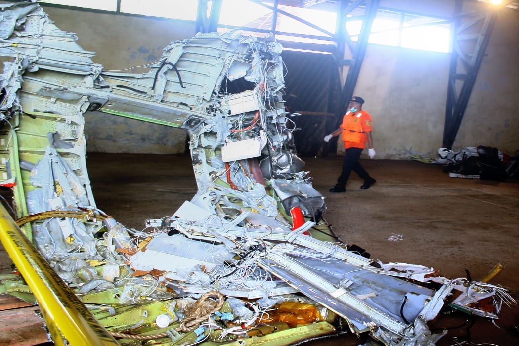 A member of Indonesia's search and rescue team walks past wreckage of AirAsia flight QZ8501 stored in a warehouse.