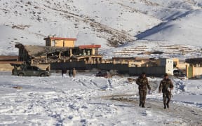 Afghan security forces walks near a site after a car bomb attack on a military base in the central province of Maidan Wardak.
