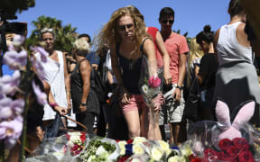 A woman lays a flower in the street of Nice to pay tribute to the victims of the Bastille Day attack.
