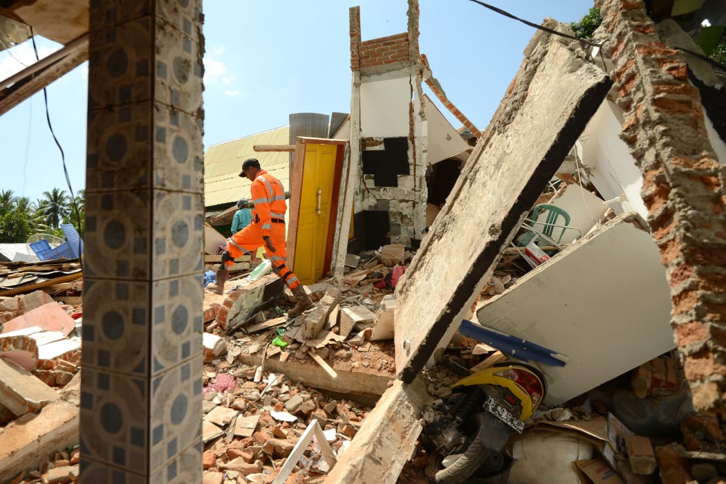 A rescue worker searches a quake damaged house at Pemenang village in northern Lombok, on 7 August, two days after the area was struck by an earthquake.