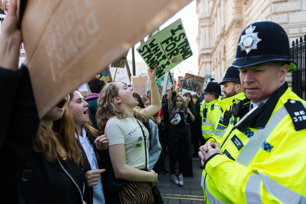 Police watch students in the London as they protest over climate change.