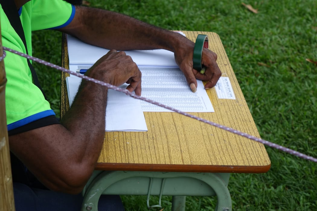 A polling officer reads an electoral roll to call out names for voters to step into the polling booth during the Papua New Guinea 2017 election.