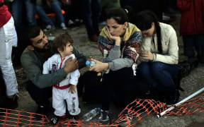 Refugees and migrants rest after arriving at the Greek island of Lesbos after crossing the Aegean sea from Turkey on October 4, 2015. AFP PHOTO / ARIS MESSINIS