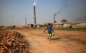 A child is carries drinking water for a brickyard worker.