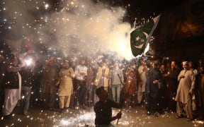 A Pakistani man waves the national flag as people celebrate after the ceasefire between Pakistan and India.