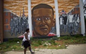 A woman walks past a mural of Freddie Gray in Baltimore.
