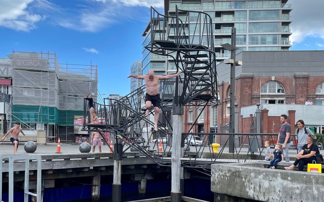 Divers jump off the platform at Taranaki Wharf, Wellington CBD