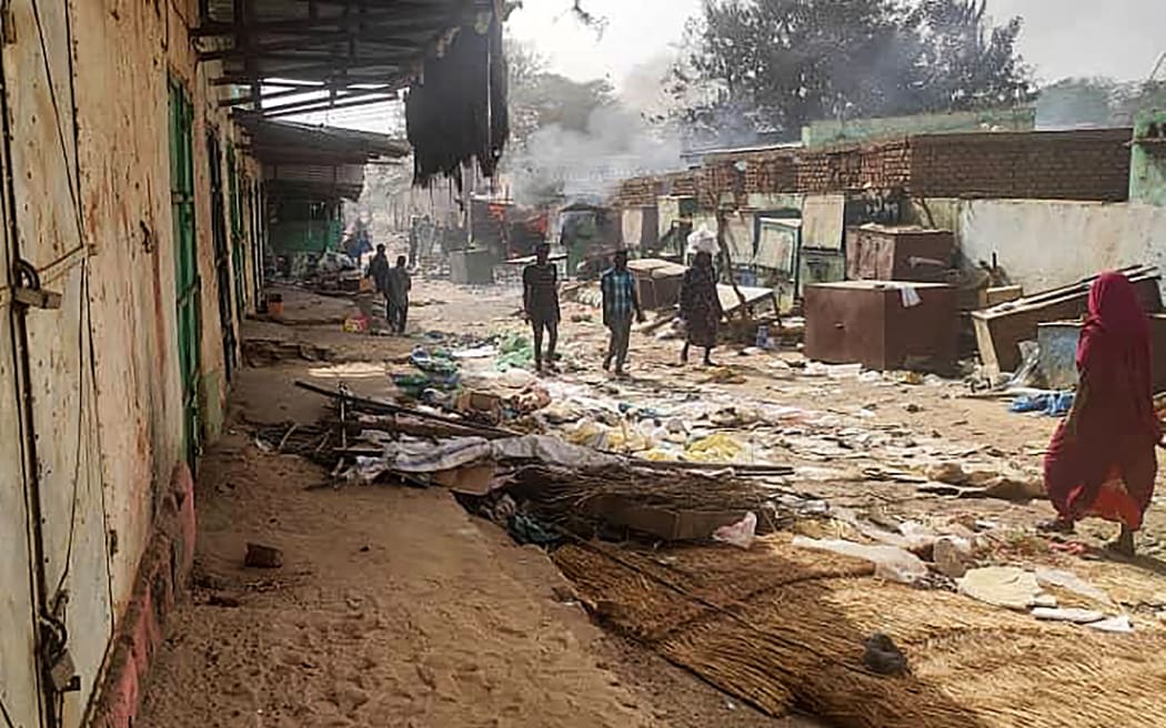 People walk among scattered objects in the market of El Geneina, the capital of West Darfur, as fighting continues in Sudan between the forces of two rival generals, on April 29, 2023. At least 96 people were reported to have been killed in El Geneina this week, the UN said, as fierce fighting between Sudan's army and paramilitaries entered a third week, violating a renewed truce. (Photo by AFP)