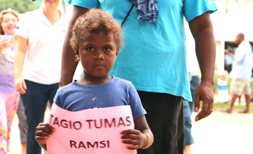 A boy holds a sign saying "Thank you very much RAMSI"