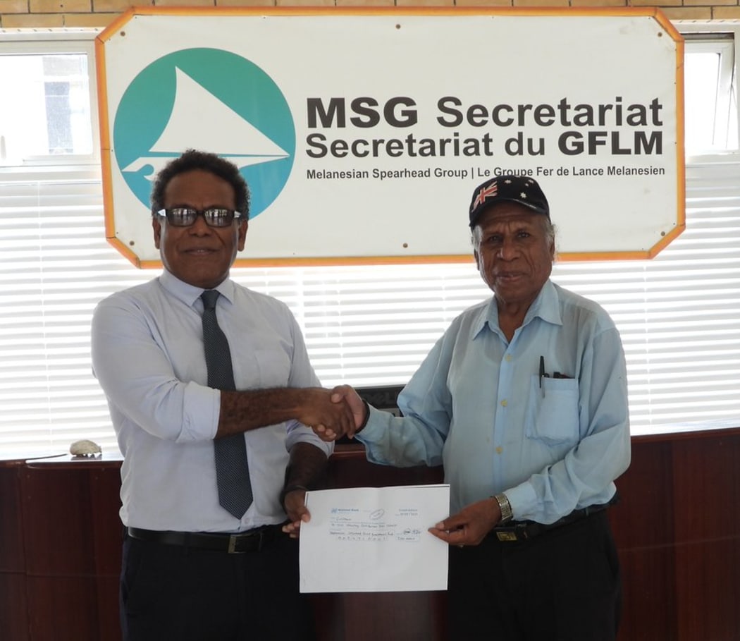 The acting Director-General of the Melanesian Spearhead Group, George Hoa'au (left) receives a contribution to the MSG Secretariat from the ULMWP representative Freddie Waromi.