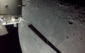 portion of the far side of the Moon looms large just beyond the Orion spacecraft in this image taken on the 20th day of the Artemis I mission by a camera on the tip of one of Orion’s solar arrays.