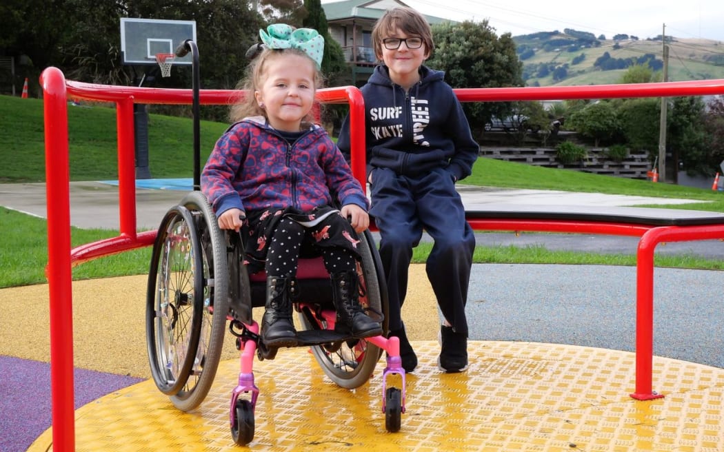 Joshua Rudd and his friend Scarlette with the new "inclusive roundabout" at his local park in Dunedin.